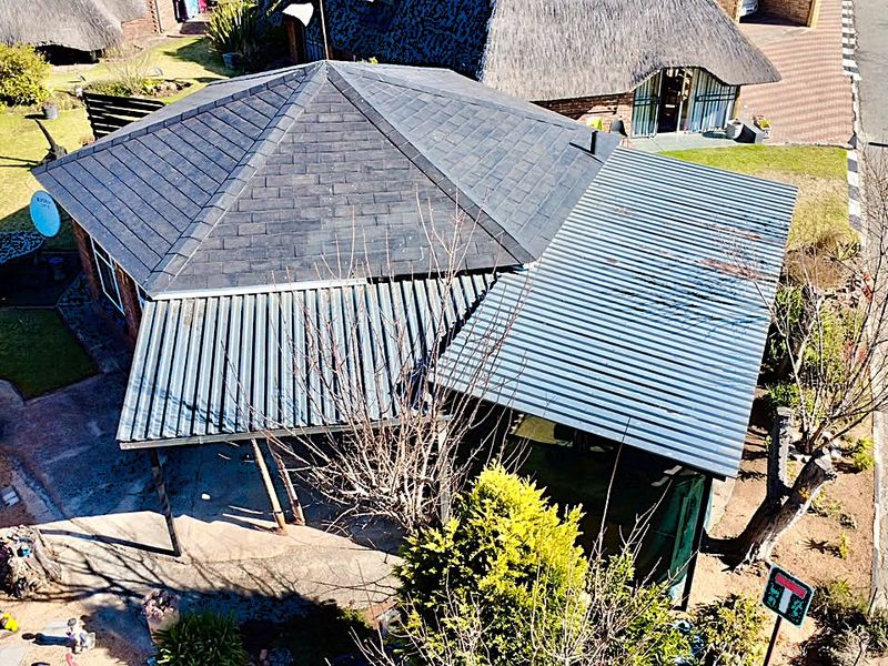 Aerial view of the property showing the roof structure, including a tiled section and a corrugated metal roof over the patio area.