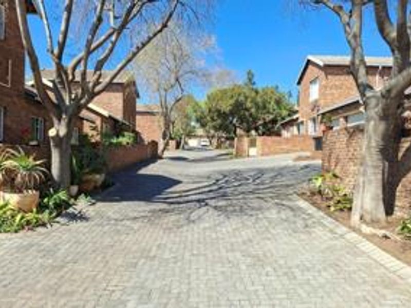 A view of the paved driveway and surrounding facebrick townhouse units within the residential complex.