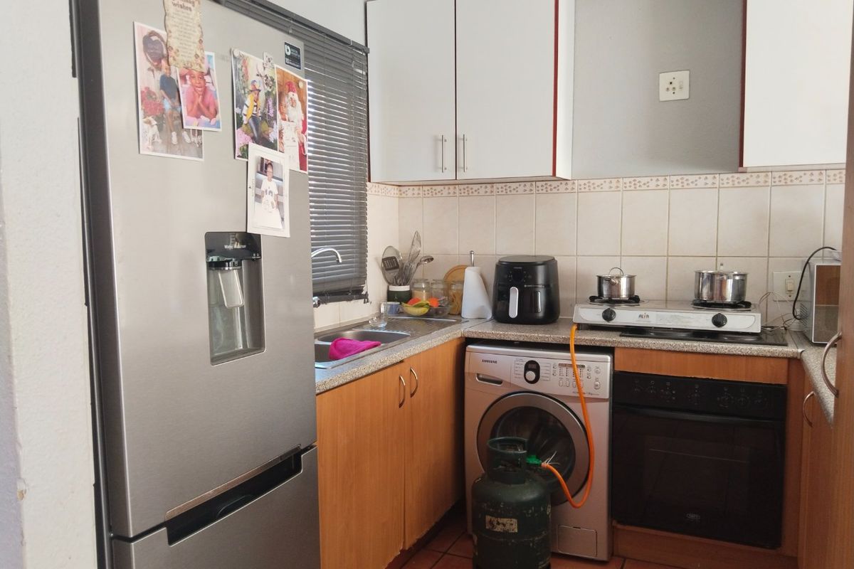 Compact kitchen featuring built-in cabinetry, tiled backsplash, gas hob, and integrated oven, providing a functional workspace with essential fixed appliances.