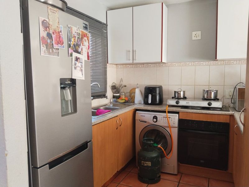 Compact kitchen featuring built-in cabinetry, tiled backsplash, gas hob, and integrated oven, providing a functional workspace with essential fixed appliances.