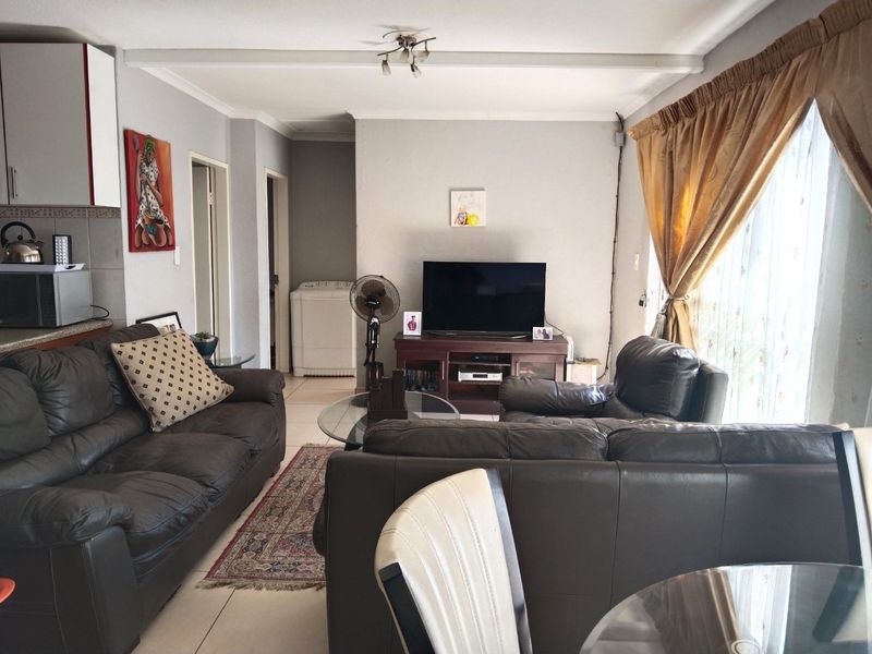 Open plan living area featuring tiled flooring and integrated kitchen cabinetry, providing a functional and connected space for daily living.