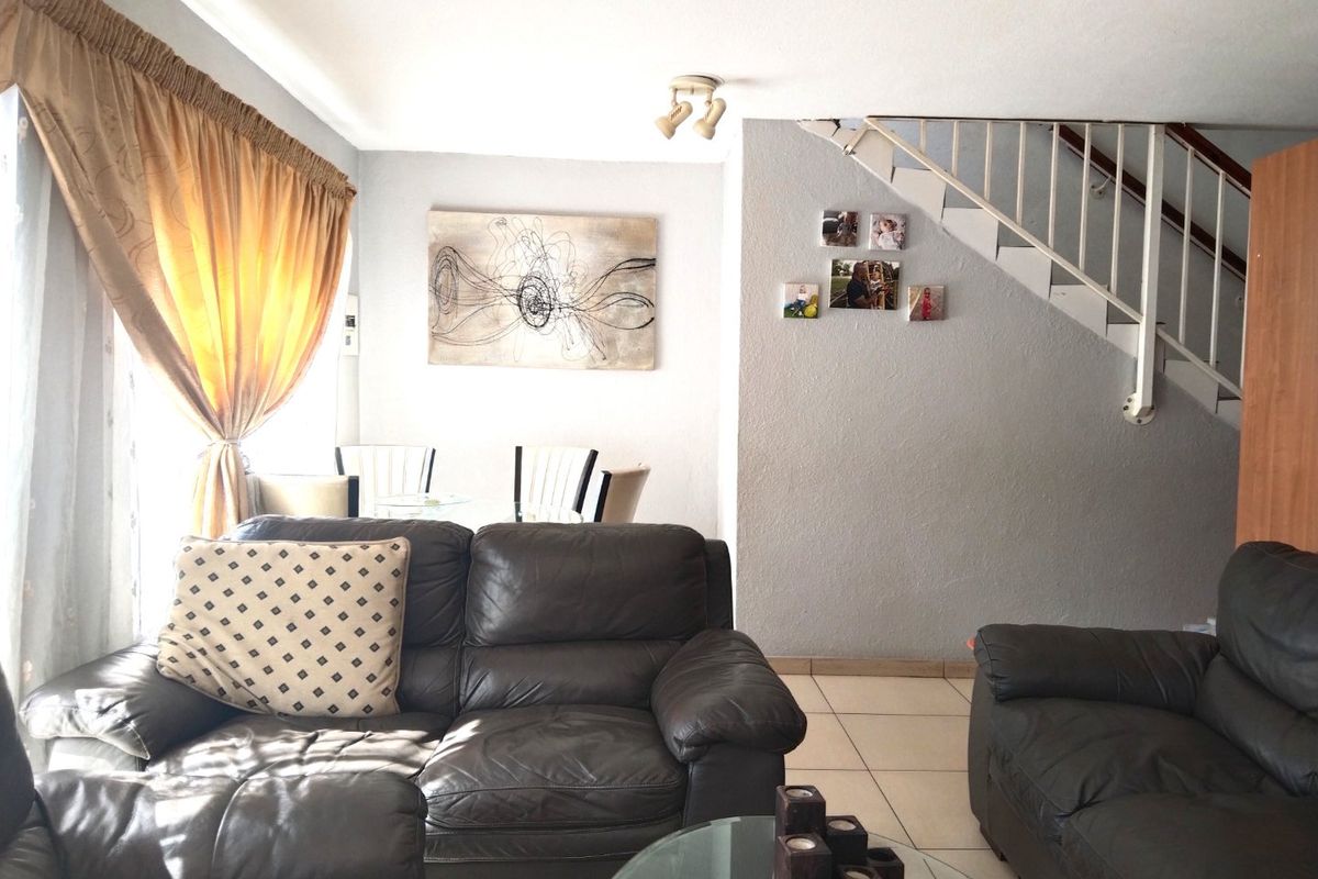A living room area featuring tiled flooring and an open staircase, providing a functional layout for the townhouse.