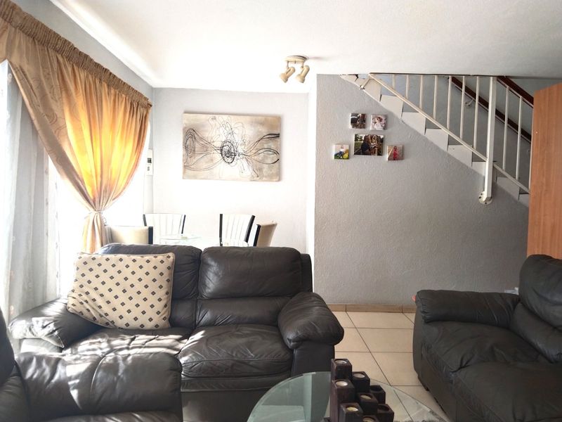A living room area featuring tiled flooring and an open staircase, providing a functional layout for the townhouse.