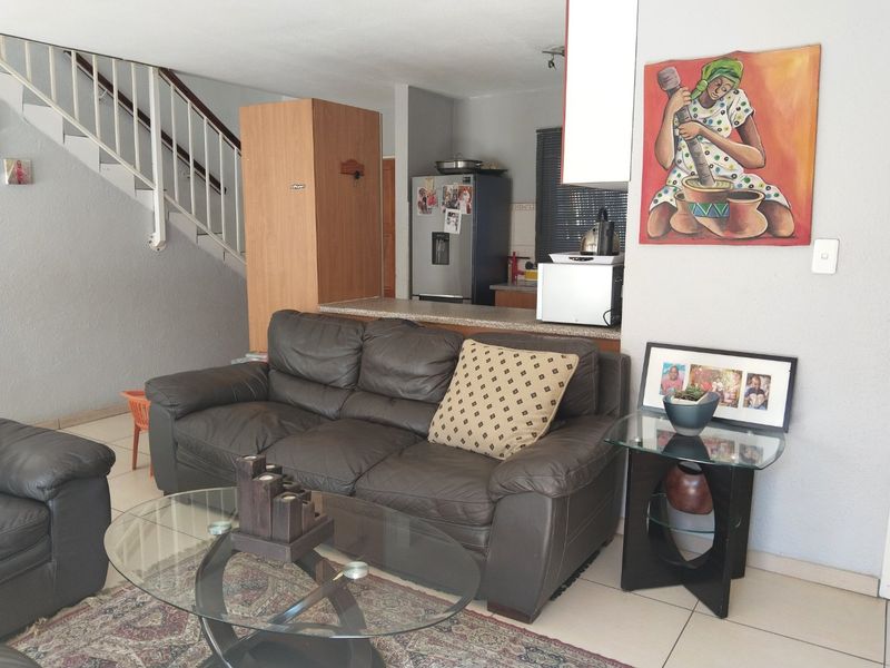 Open plan living area featuring a staircase, tiled flooring, and a compact kitchen with stone countertops.