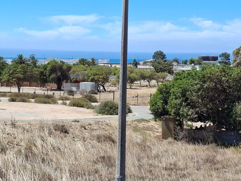 A wide-angle view of the vacant residential land, featuring natural vegetation, perimeter fencing, and distant coastal scenery.