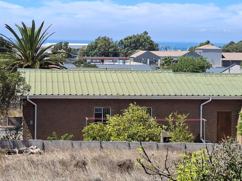Rear view of a residential property featuring a brick facade, corrugated metal roof, and a precast concrete boundary wall.