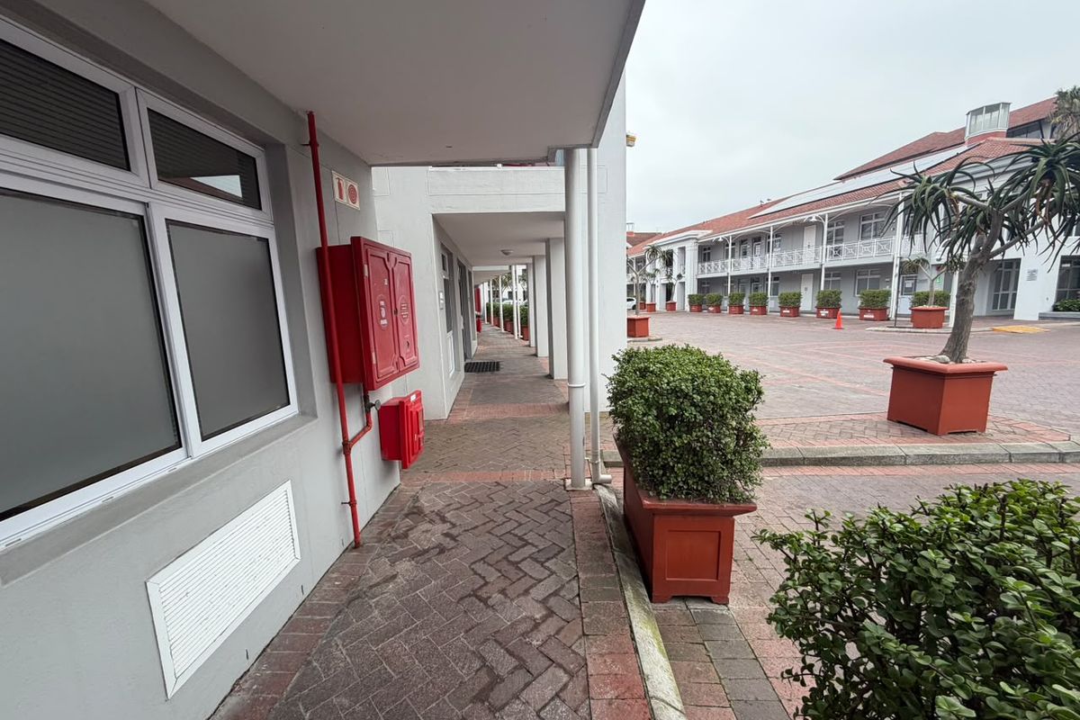 A well-maintained commercial courtyard featuring a covered walkway, brick paving, and integrated fire safety equipment.