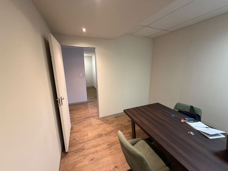 A functional office space featuring wood-look laminate flooring, recessed lighting, and a suspended ceiling, providing a clean and professional work environment.