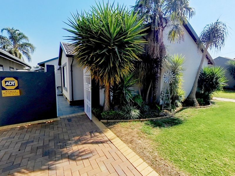 Front view of the property featuring a paved driveway, secure gated entrance, and a well-maintained garden area.