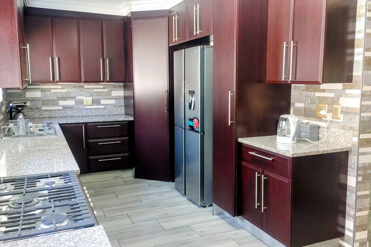 Modern kitchen featuring dark wood cabinetry, granite countertops, a gas hob, and a decorative tiled backsplash.