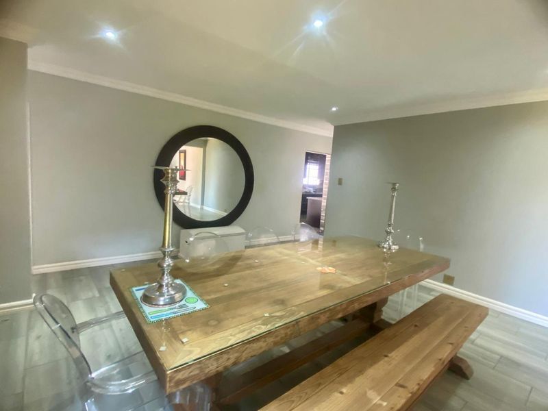 A well-lit dining room featuring neutral grey walls, crown molding, and modern tiled flooring, providing a clean and versatile space for entertaining.