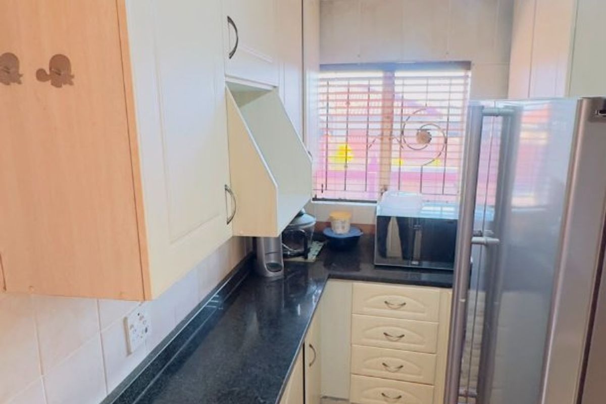 Compact kitchen featuring built-in cabinetry, dark laminate countertops, tiled flooring, and a decorative ceiling rose.