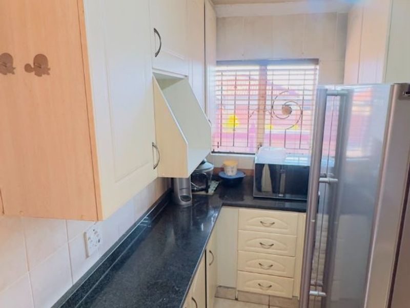 Compact kitchen featuring built-in cabinetry, dark laminate countertops, tiled flooring, and a decorative ceiling rose.