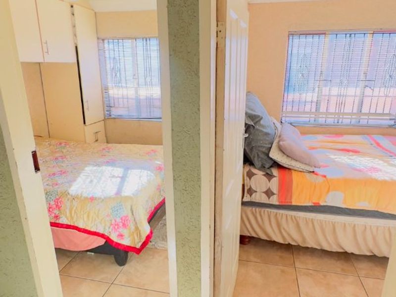 View through doorways into two bedrooms featuring tiled flooring and built-in cupboard storage.