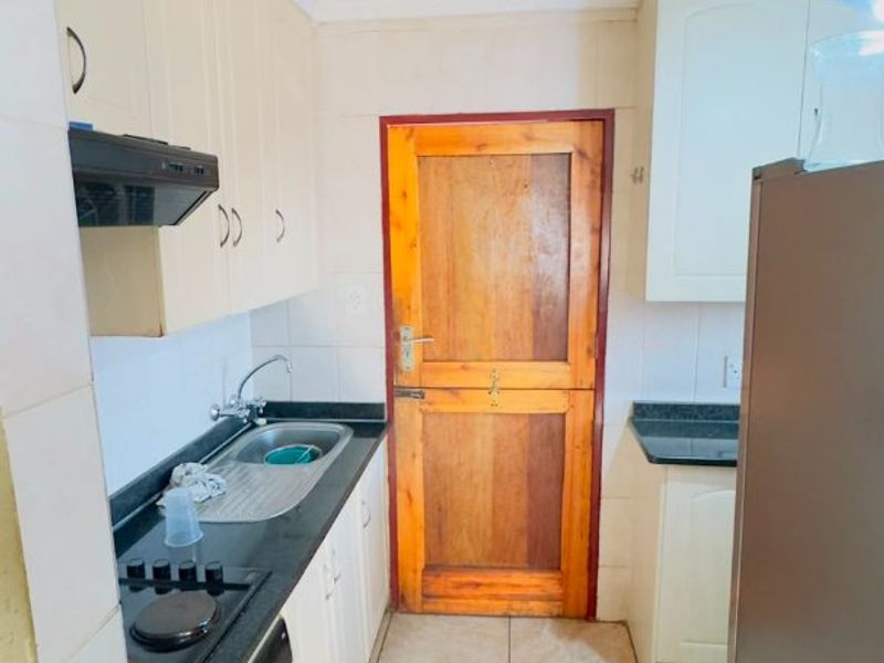 A functional kitchen featuring built-in cabinetry, granite countertops, a built-in oven with hob, and tiled flooring, providing a practical workspace.
