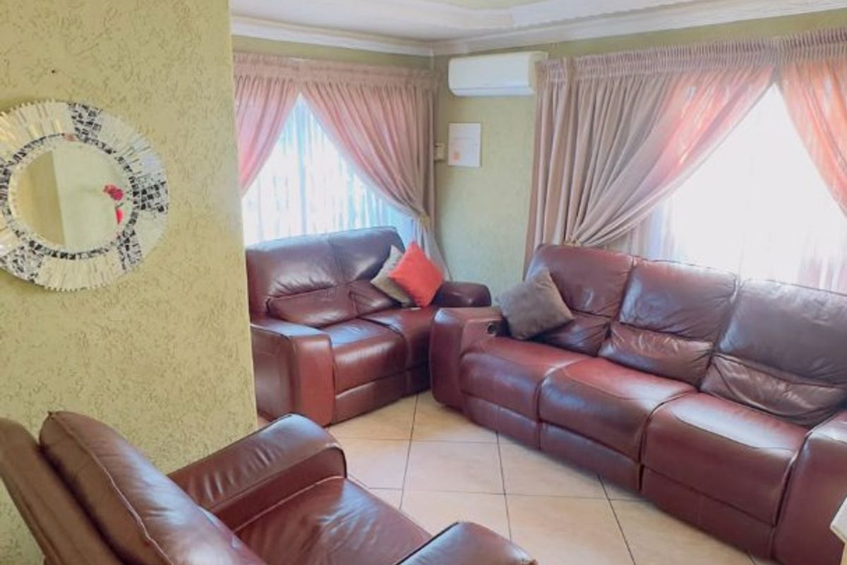 A living room featuring tiled flooring, decorative ceiling molding, a ceiling rose, and a wall-mounted air conditioning unit.