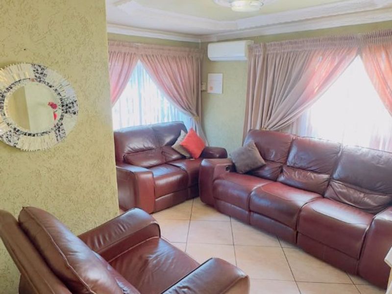 A living room featuring tiled flooring, decorative ceiling molding, a ceiling rose, and a wall-mounted air conditioning unit.