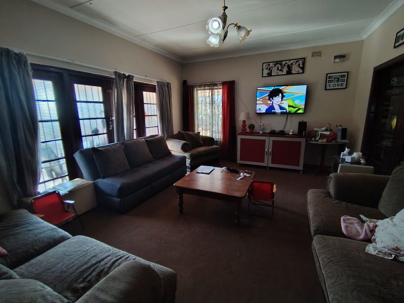 A spacious living room featuring classic french doors that provide natural light and access to the exterior, complemented by traditional ceiling coving.