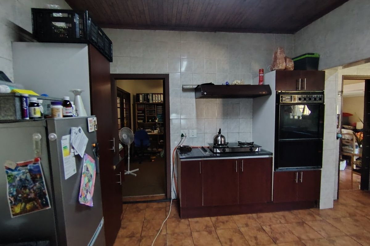 A dated kitchen featuring dark wood cabinetry, a built-in oven, gas hob, tiled backsplash, and timber ceiling, requiring modernization and electrical safety improvements.