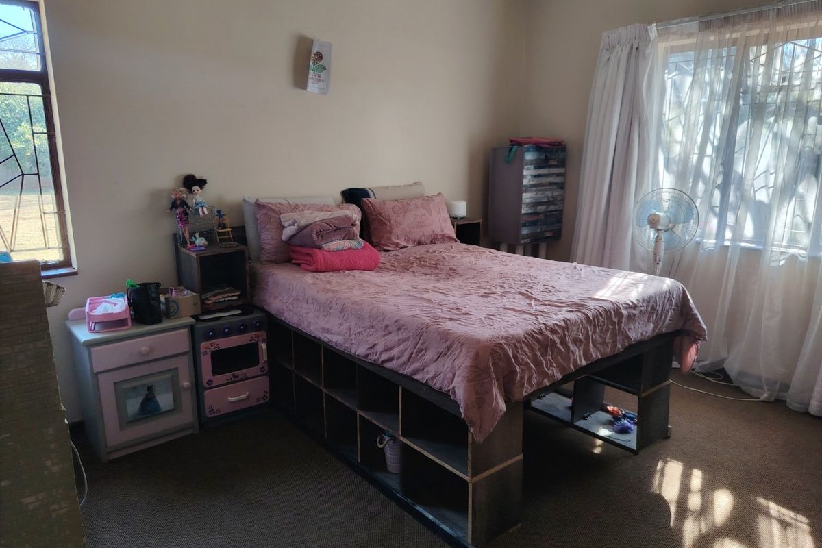 A standard bedroom featuring neutral wall finishes, carpeted flooring, and natural light provided by two windows with curtain rails.
