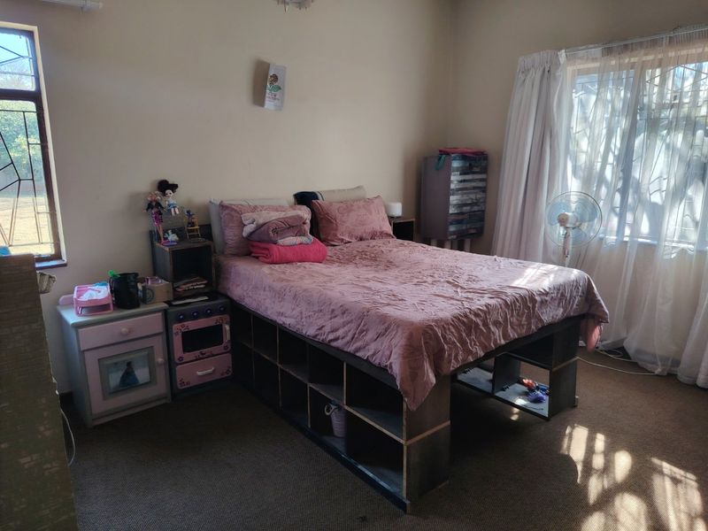 A standard bedroom featuring neutral wall finishes, carpeted flooring, and natural light provided by two windows with curtain rails.