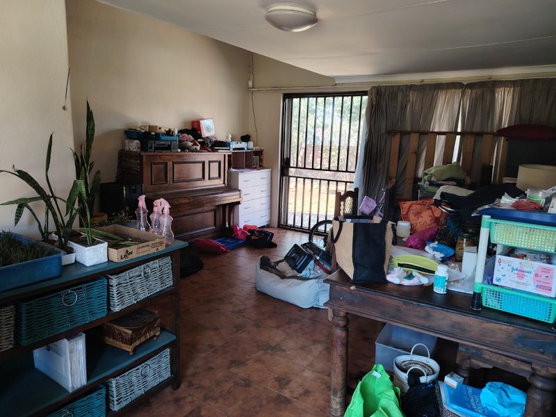A living area featuring tiled flooring and a security gate leading to the exterior, requiring cosmetic updates to improve the overall aesthetic.