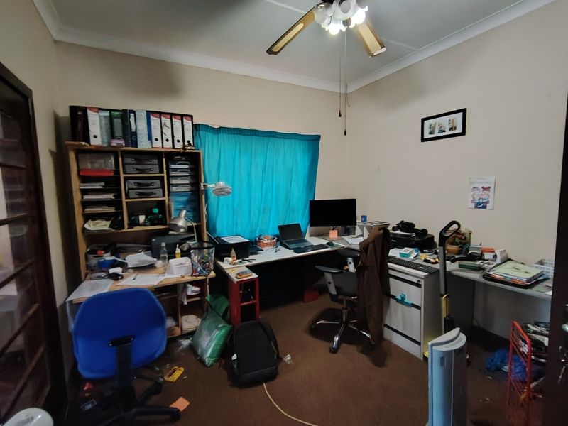 A functional home office space featuring a ceiling fan and window, providing a dedicated area for work or study.
