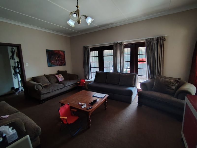 Spacious living room featuring classic coving, a central ceiling light fixture, and timber-framed french doors providing access to the exterior.
