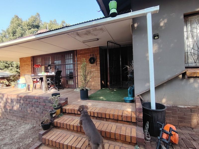 A covered brick patio area featuring steps, a low retaining wall, and security gate access to the main dwelling.