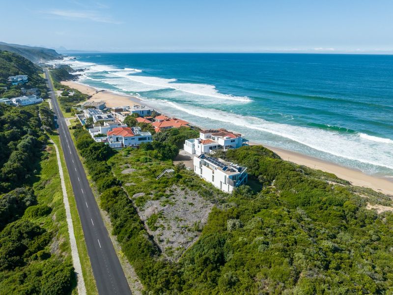 Aerial view of a vacant residential plot situated along the coastline, featuring natural vegetation and direct proximity to the beach and ocean.