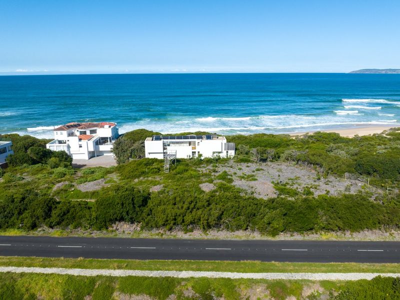 Aerial view of a coastal residential property featuring solar panels, situated near the beach with direct ocean views.