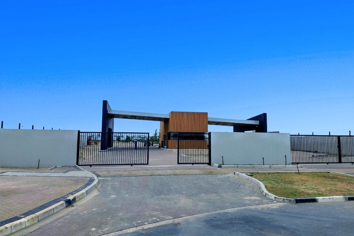 A modern residential estate entrance featuring a secure gate, perimeter walls, and a contemporary guard house structure.