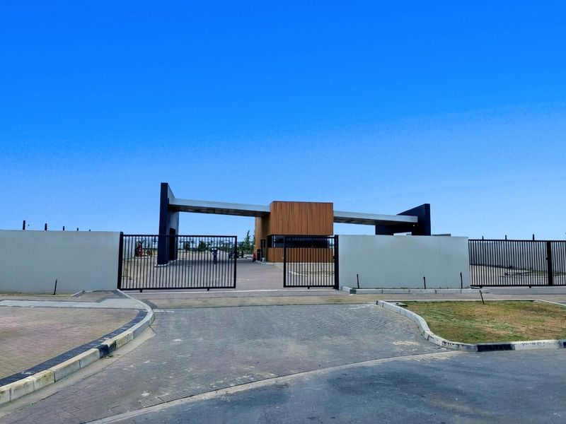 A modern residential estate entrance featuring a secure gate, perimeter walls, and a contemporary guard house structure.