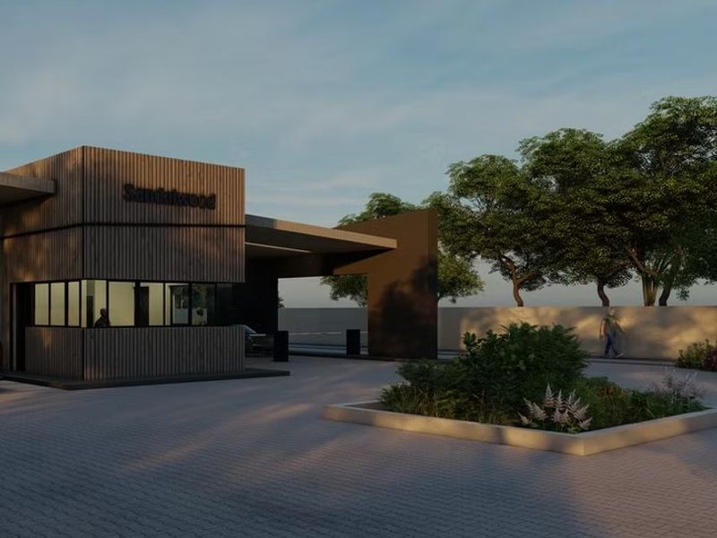 Modern security gatehouse entrance for Sandalwood estate featuring contemporary timber-slat cladding, paved driveway, and landscaped garden beds.