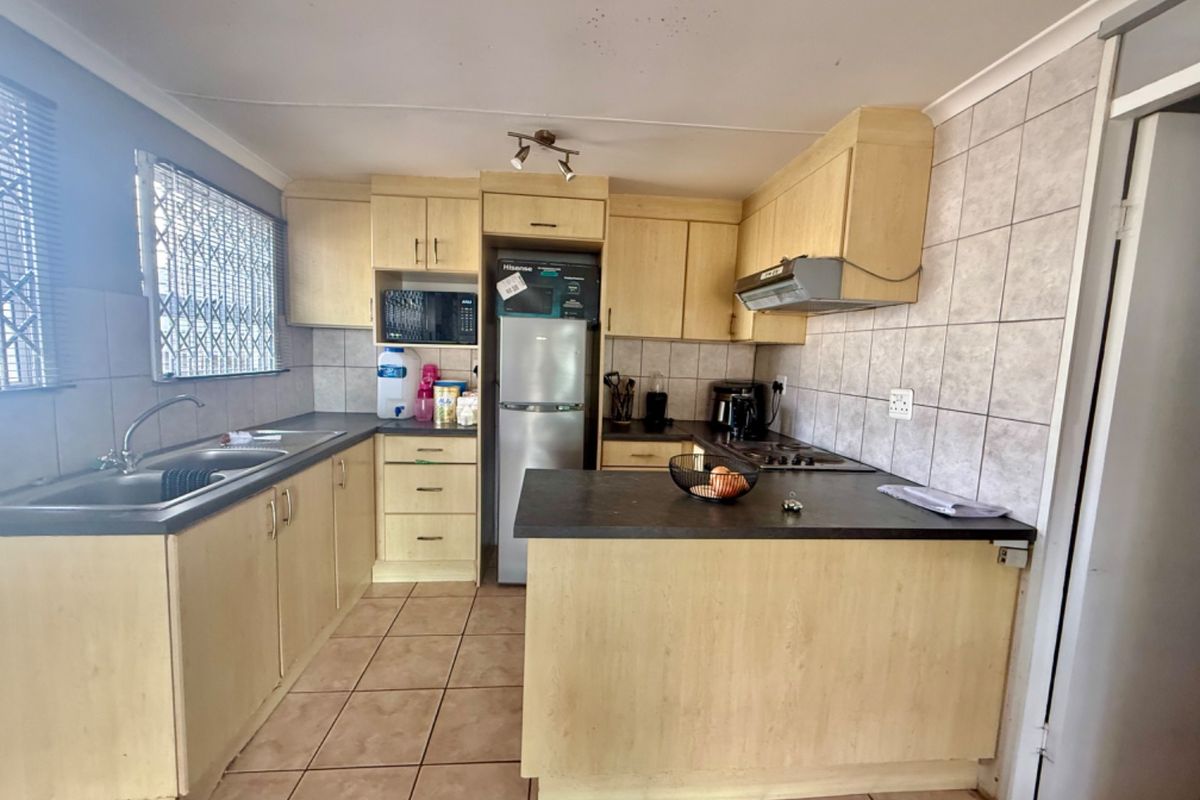 Functional kitchen featuring laminate cabinetry, tiled backsplash, built-in hob and oven, and a breakfast counter, offering a practical layout for daily meal preparation.