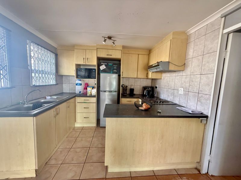Functional kitchen featuring laminate cabinetry, tiled backsplash, built-in hob and oven, and a breakfast counter, offering a practical layout for daily meal preparation.