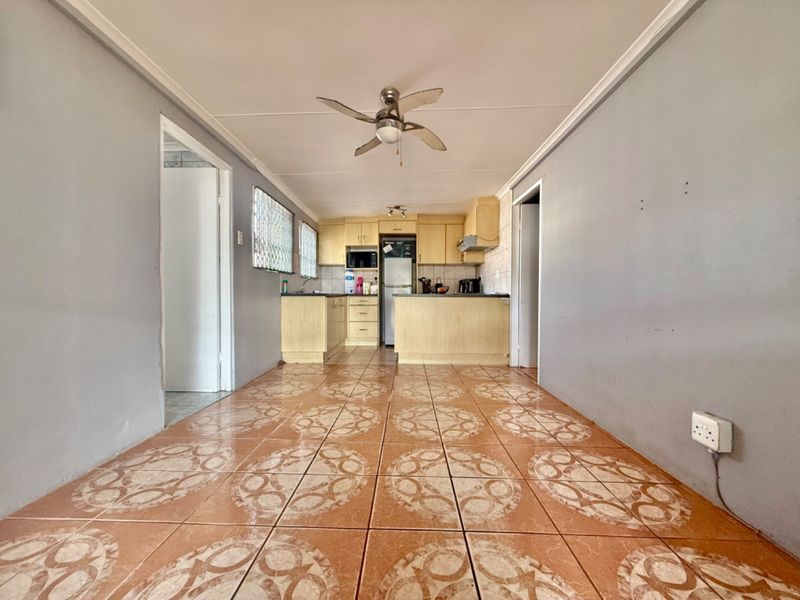 Open plan kitchen and living area featuring tiled flooring, built-in cabinetry, and a ceiling fan, offering a functional layout ready for modernization.