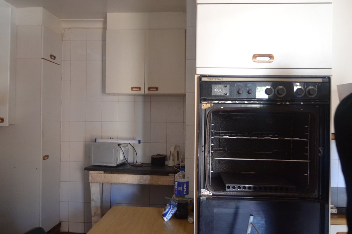 A dated kitchen featuring built-in oven, wall-mounted cabinetry, and tiled backsplash, offering significant potential for modernization and renovation.