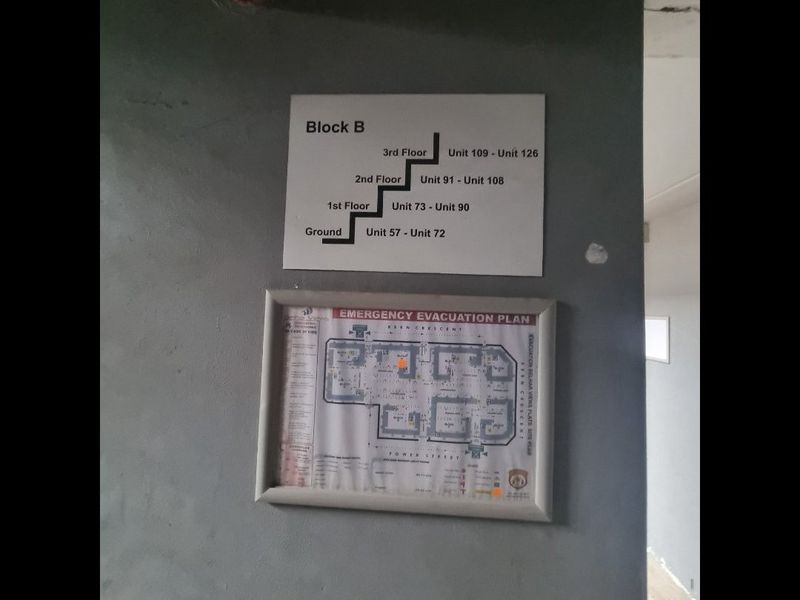 A hallway wall displaying building unit numbering and an emergency evacuation plan for Block B.
