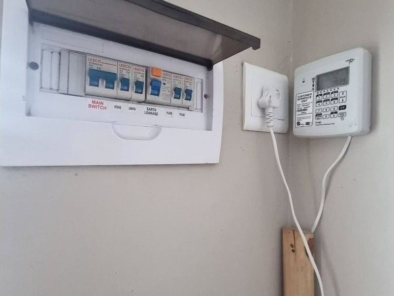 A utility wall featuring a standard electrical distribution board and a prepaid electricity meter interface unit.