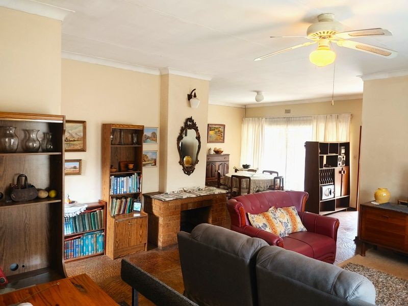 Spacious open-plan living and dining area featuring a brick fireplace, ceiling fan, and large sliding doors providing natural light.