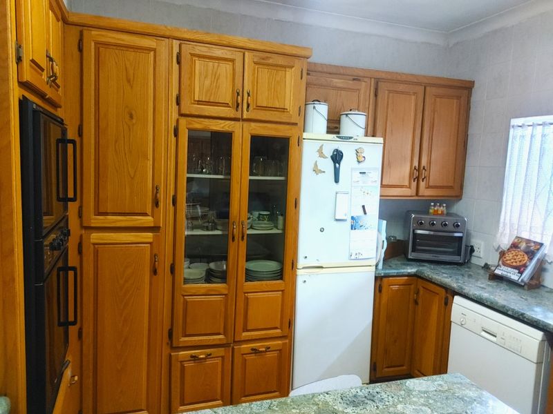 A functional kitchen featuring traditional wooden cabinetry, built-in oven, and stone-look countertops, offering a classic layout with ample storage space.