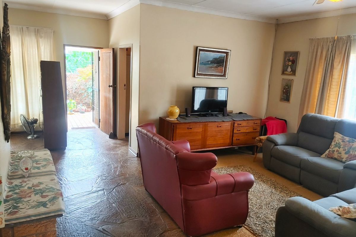 A living room featuring natural stone flooring, cove cornicing, and direct access to an outdoor area through a timber door.