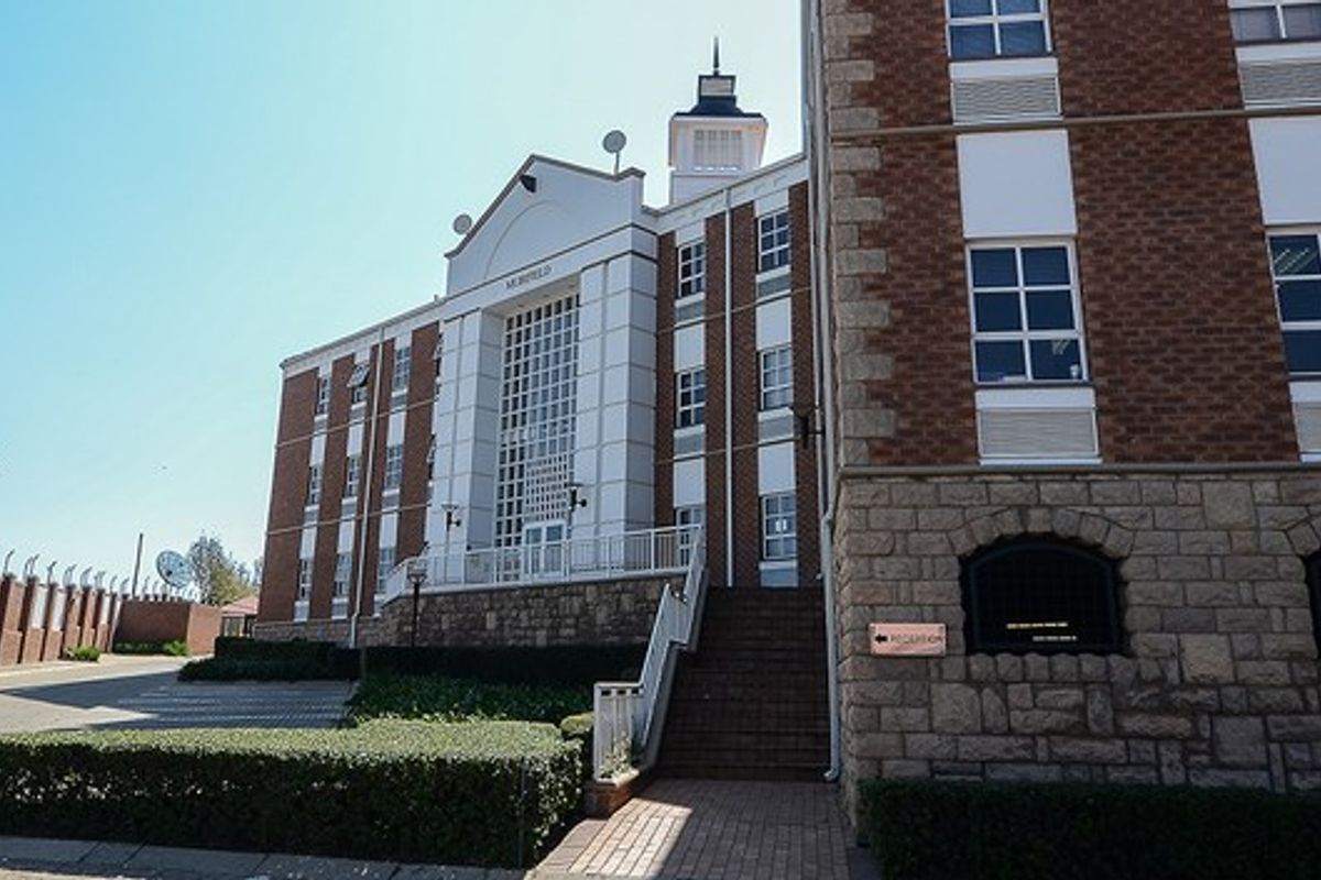Front elevation of a multi-story commercial building featuring brick and stone masonry, a central entrance staircase, and landscaped perimeter grounds.