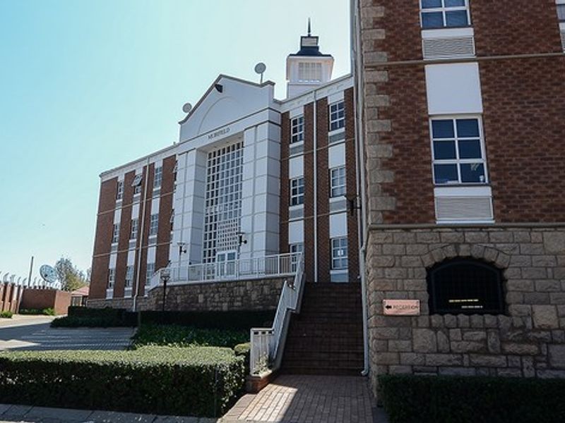 Front elevation of a multi-story commercial building featuring brick and stone masonry, a central entrance staircase, and landscaped perimeter grounds.