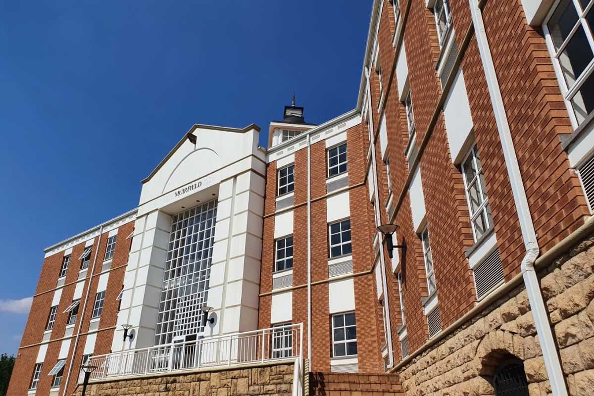 A low-angle view of the Muirfield commercial building facade, featuring a combination of red brick, white architectural detailing, and a stone-clad base.