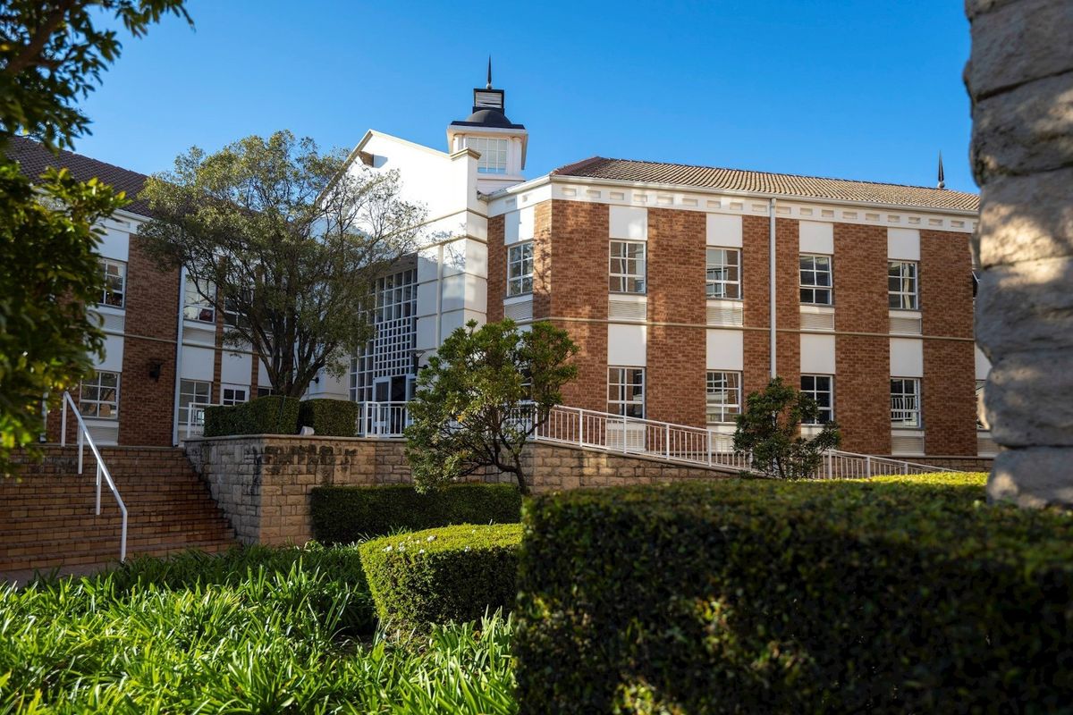A well-maintained commercial building featuring a classic brick facade, a central cupola, and accessible ramp entry with landscaped garden surroundings.