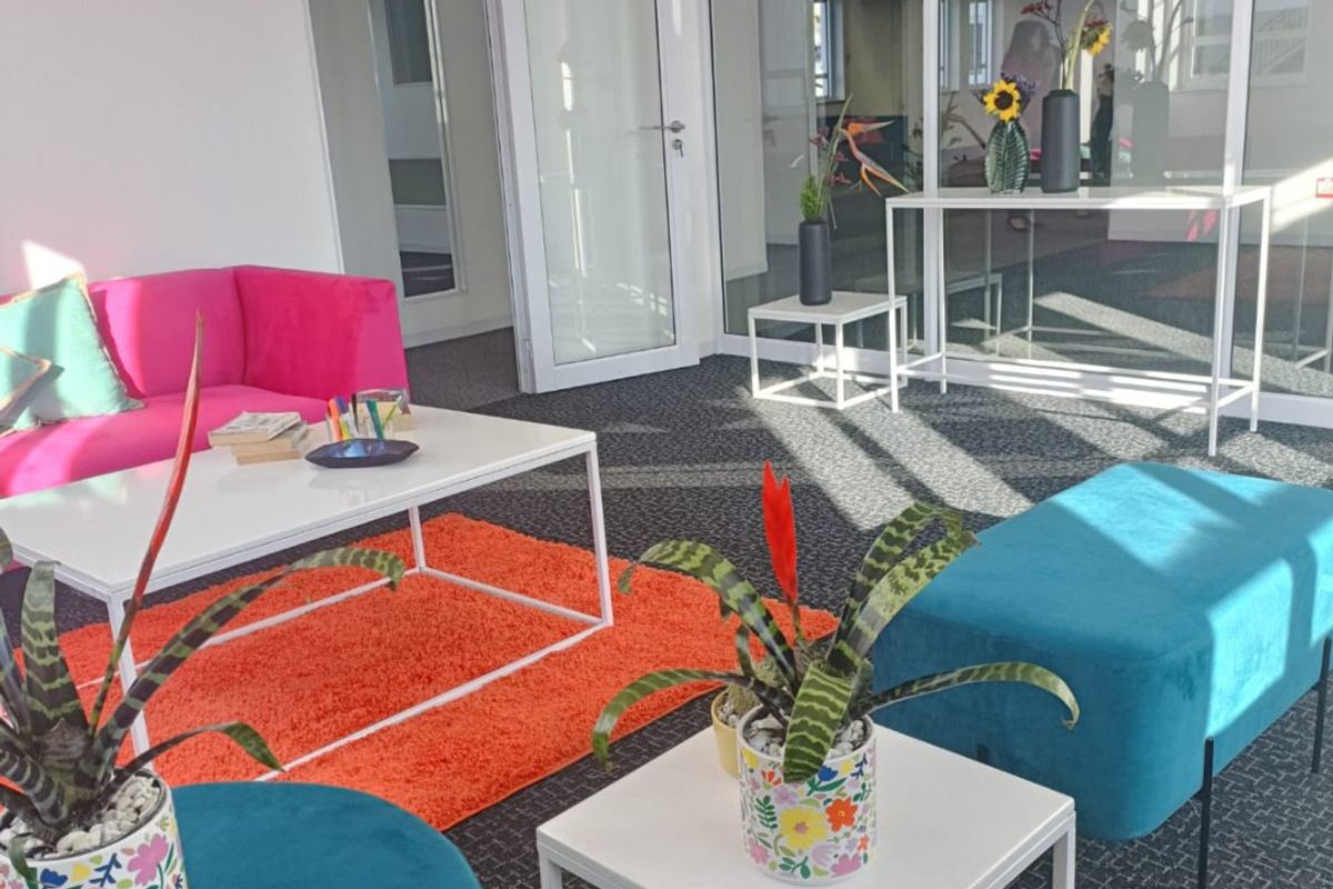 A modern commercial office breakout area featuring glass partitioning, carpeted flooring, and a bright, open-plan layout suitable for collaborative work.