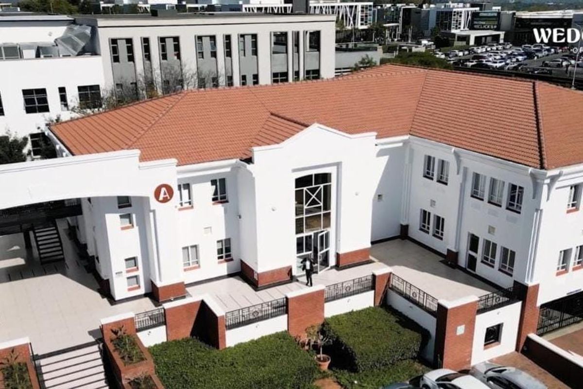 Aerial view of a commercial office park building featuring a tiled roof, brick and white facade, and paved courtyard entrance.