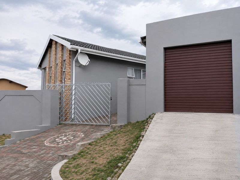 Front view of the property featuring a paved driveway, a single garage with a roller door, and a secure gated entrance.